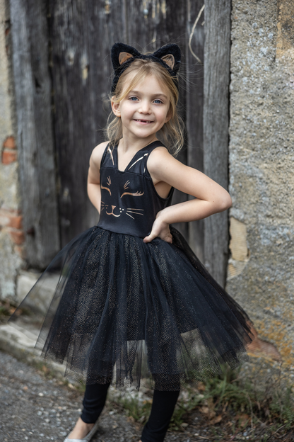 Our new Black Cat Dress &amp; Headband is the purrfect ensemble for your little feline aficionado! The dress features a sleek black design adorned with a charming cat face printed in shimmering rose gold on the chest. Its skirt dazzles with golden heat-sealed sparkles, adding a touch of glamour to every twirl. And what&