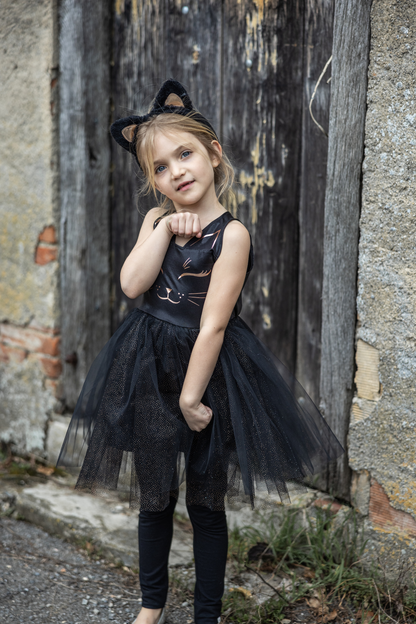 Our new Black Cat Dress &amp; Headband is the purrfect ensemble for your little feline aficionado! The dress features a sleek black design adorned with a charming cat face printed in shimmering rose gold on the chest. Its skirt dazzles with golden heat-sealed sparkles, adding a touch of glamour to every twirl. And what&