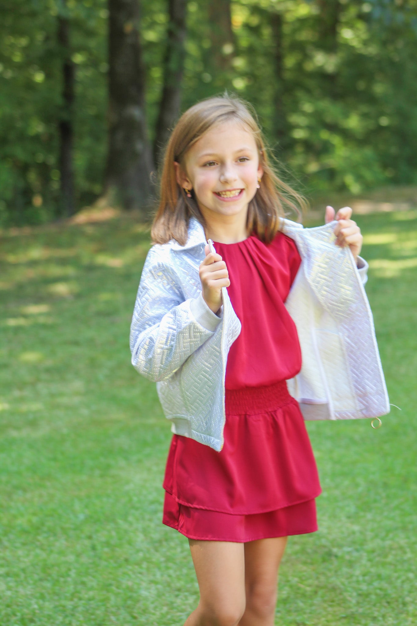 Delicate and dreamy, this silky dress is made just for girls who love a touch of elegance. It has soft pleats that gather gently at the neckline, creating a sweet, textured look. The bloused top flows beautifully over a fitted waist, introducing her to an appropriate and classic figure flattering look. Its comfy fabric makes it easy to move, twirl, and play—while still looking polished for special occasions or family celebrations.